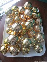 Tray filled with reflective gold glass Christmas ball ornaments