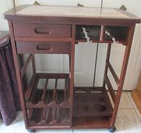Full view of wooden bar cart showing drawers, wine rack, bottle holder, and casters