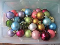Top view of plastic bin filled with multicolored ball ornaments, many with tags