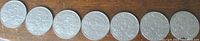 Seven Canadian 5 cent coins laid in a row reverse side up