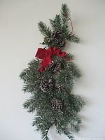 Full view of faux pine swag showing cones, bow, greenery