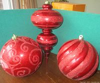 All three oversized red ornaments on table