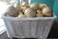 White wicker basket filled with gold metallic ball ornaments
