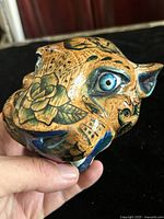 Front three-quarter view showing painted designs and blue eye