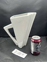 Front view of pitcher beside soda can for scale