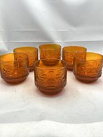 Front view of six amber CB2 tiki glasses