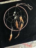 Full view of dreamcatcher showing twig hoop, web, turquoise, feathers