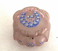 Top view showing pink glass lid with blue forget-me-not enamel and pink ribbon
