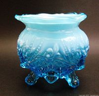 Front view showing opalescent blue body, embossed pattern, three feet