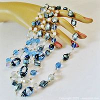 Necklace draped on mannequin hand showing bead variety and colors