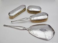 Full view of all four vanity pieces showing sterling backs and bristles