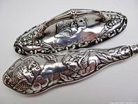 Close view of nail buffer top and button hook handle showing cherub repousse and hallmarks