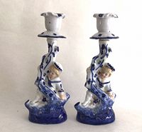 Front view of both porcelain candlesticks showing sailor boy figures and blue glaze