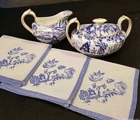 Creamer, lidded sugar bowl, three linen napkins displayed