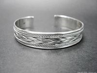 Front view of sterling silver cuff showing braided centre and chevron borders