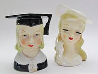 Front view of both head vases showing facial details and accessories