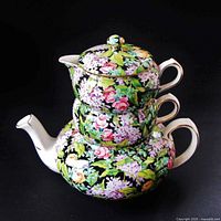 stacked view of teapot, creamer, sugar bowl, lid showing floral chintz pattern