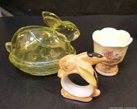 Group view of yellow glass rabbit dish, ceramic rabbit napkin ring, and decorated egg cup