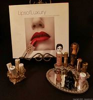 Group shot of book, lipstick holders, tubes and Dali perfume on dresser