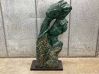 Full view of patinated metal sculpture on black stone base