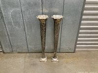 Front view of both tall silver-plated floor vases