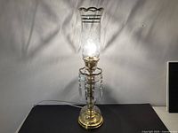 Full view of lamp lit showing etched chimney, prisms, brass and glass construction