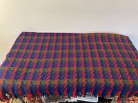 Full view of folded multicolor chevron wool throw with fringe