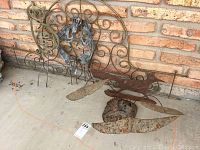 Five metal lawn decor pieces shown, including a large decorated wall piece with human figures and scrollwork, and four freestanding rusted and curved metal pieces.