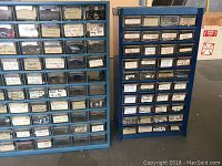 Front view of two blue metal tool organizers with multiple small plastic drawers labeled with various hardware items such as screws and washers.