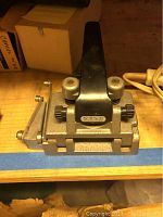 Metal 16mm film splicer with handle and adjustment knobs on a wooden surface.