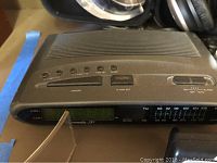 Close-up of vintage AM/FM radio clock showing control buttons and digital display, with some wear visible