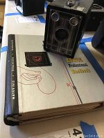 Brownie Junior Six-20 camera sitting on top of the Kodak Professional Handbook, showing both items in the lot.