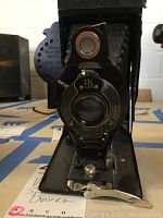 Front view of camera with lens and shutter mechanism visible.