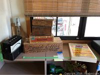 Photo showing vintage voltmeter, Riverside Cutter wooden box, smaller wooden boxes, Sears Roebuck catalog, and toy tractor.