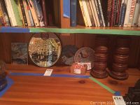 Photo showing various items on a wooden shelf including the Hamms Beer round mirror, Cadbury's Chocolate metal sign, coasters, distelfink figurine, and wooden candle holders.