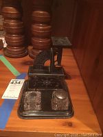 Overall view of black metal postal scale with two square crystal ink jars, showing scale with floral decorations and jars positioned on the base tray.