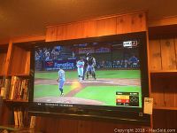 Sony Bravia 39 inch television displaying a baseball game on the screen, showing the front view of the TV mounted on a wooden wall.