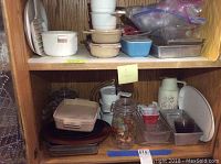 Shelf with assorted baking dishes, glassware, ceramic and plastic containers, and kitchen items