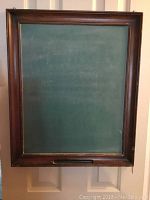 Full view of antique chalk board with dark wood frame and green chalk surface