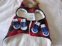 Dog coat laid flat showing exterior plaid, white lining, hood, with socks placed on top