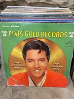 Front cover Elvis' Gold Records Volume 4 with stack of additional LPs behind