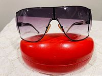 Front view of Valentino shield sunglasses on red hard case
