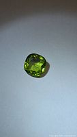 Top view of cushion cut peridot gemstone showing apple green color