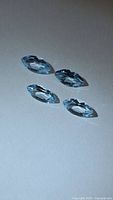 Four marquise blue topaz gemstones on neutral background