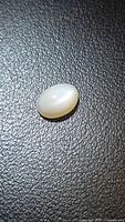 Top view of oval cabochon moonstone on black surface
