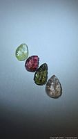 Four carved leaf-shape tourmalines on white background