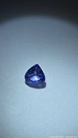 Teardrop purple-blue faceted tanzanite on light background