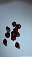 Ten round red garnets grouped on white background