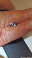 Two round violet-blue Tanzanite stones held between fingers