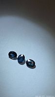 Three oval blue sapphires under spotlight